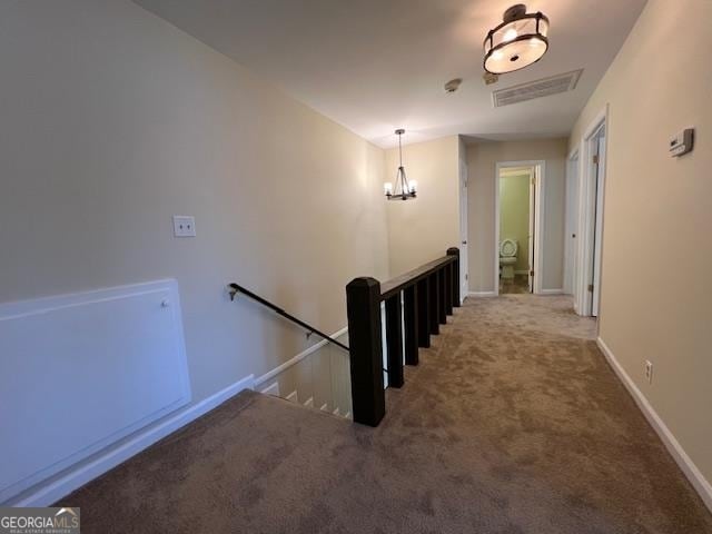 hall featuring carpet flooring and an inviting chandelier