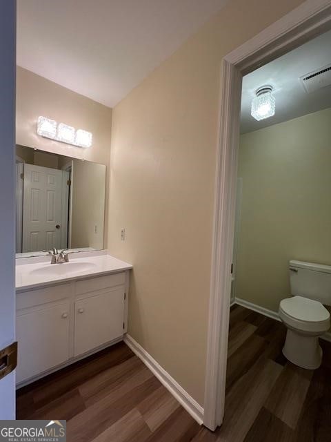 bathroom featuring toilet, hardwood / wood-style flooring, and vanity with extensive cabinet space