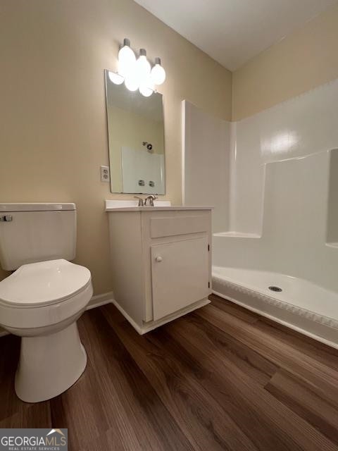 bathroom with a shower, toilet, hardwood / wood-style floors, and vanity