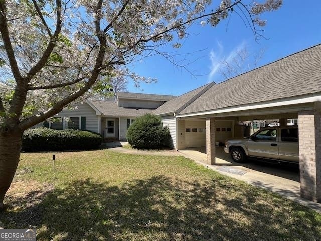 view of front of property featuring a front yard, a carport, and a garage