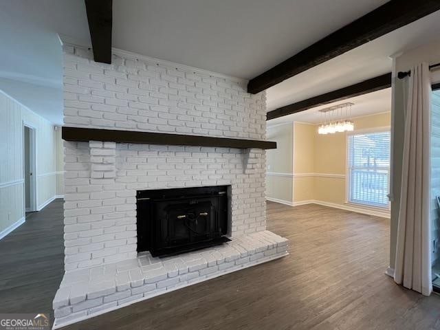 unfurnished living room featuring brick wall, dark wood-type flooring, a brick fireplace, and beamed ceiling