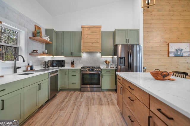 kitchen with appliances with stainless steel finishes, tasteful backsplash, light hardwood / wood-style floors, sink, and vaulted ceiling