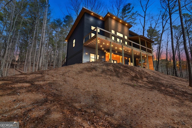 back house at dusk featuring a balcony