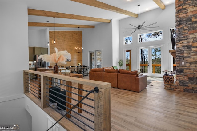 interior space featuring french doors, light hardwood / wood-style floors, high vaulted ceiling, decorative light fixtures, and ceiling fan with notable chandelier