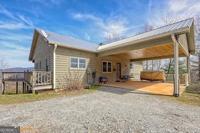 rear view of house with a wooden deck and a patio