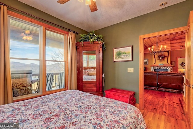 bedroom with a mountain view, wood-type flooring, and ceiling fan with notable chandelier