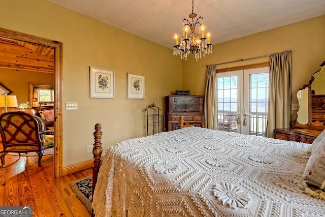 bedroom featuring access to exterior, a notable chandelier, hardwood / wood-style flooring, and french doors