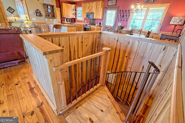 stairway with a notable chandelier, wood-type flooring, and sink