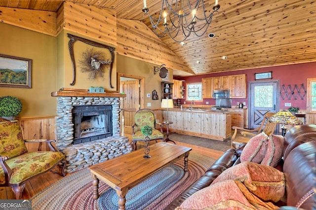 living room with wood ceiling, a stone fireplace, light hardwood / wood-style floors, wooden walls, and high vaulted ceiling