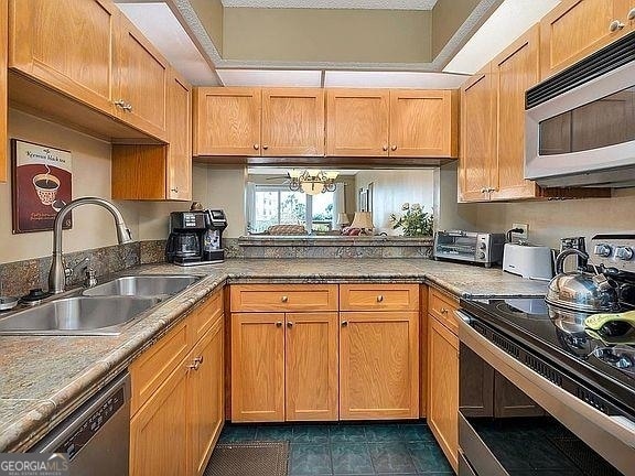 kitchen featuring dark tile floors, an inviting chandelier, appliances with stainless steel finishes, and sink