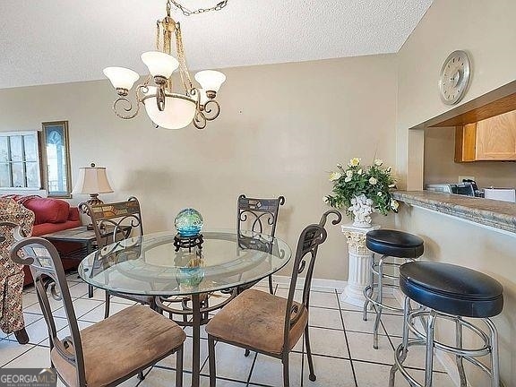 dining area featuring light tile flooring, a textured ceiling, a notable chandelier, and vaulted ceiling