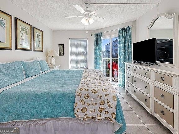 tiled bedroom featuring access to outside, a textured ceiling, and ceiling fan