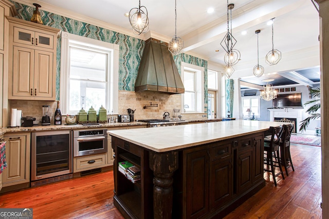 kitchen featuring dark wood-type flooring, a kitchen island, custom range hood, beverage cooler, and oven