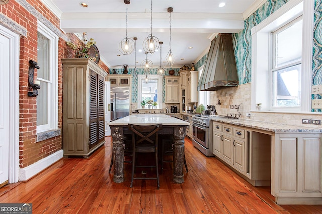 kitchen featuring hardwood / wood-style floors, a kitchen island, premium range hood, plenty of natural light, and high quality appliances