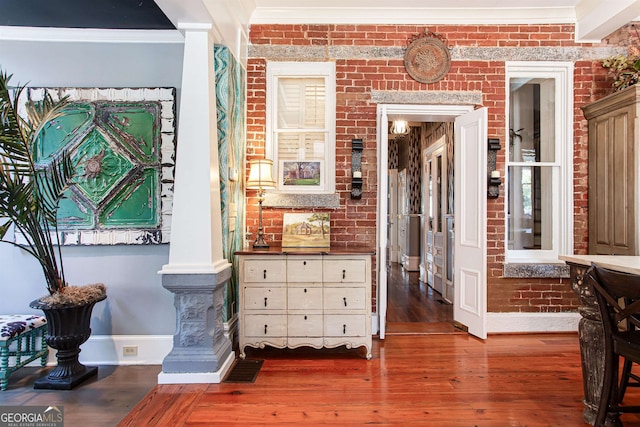 interior space featuring crown molding, brick wall, and dark hardwood / wood-style floors