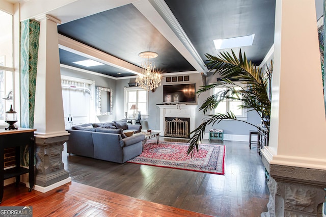 living room with ornamental molding, an inviting chandelier, dark wood-type flooring, and ornate columns