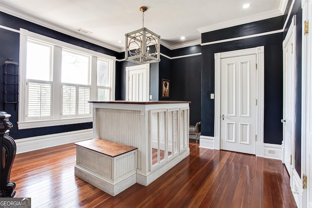 corridor with ornamental molding, an inviting chandelier, and dark wood-type flooring