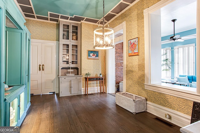 interior space with dark hardwood / wood-style flooring, ornamental molding, and ceiling fan with notable chandelier