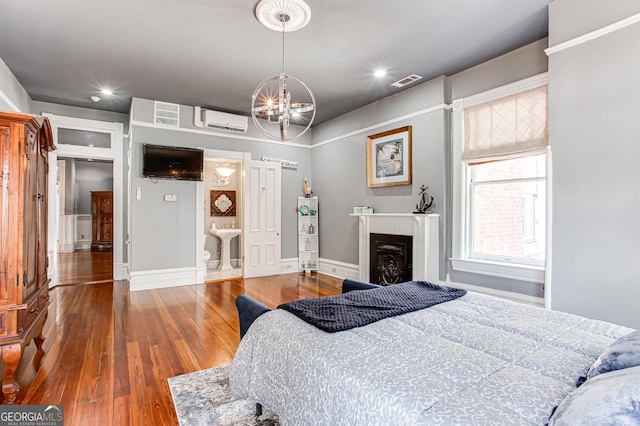 bedroom with an inviting chandelier, an AC wall unit, and hardwood / wood-style flooring