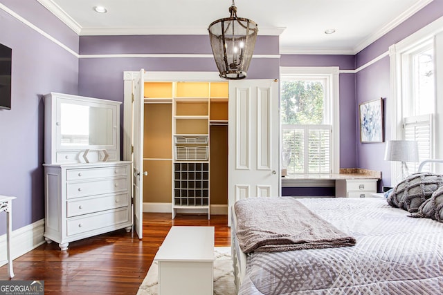 bedroom with crown molding, dark wood-type flooring, a chandelier, a closet, and a walk in closet