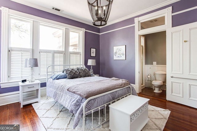 bedroom with ornamental molding, connected bathroom, dark hardwood / wood-style floors, and a chandelier