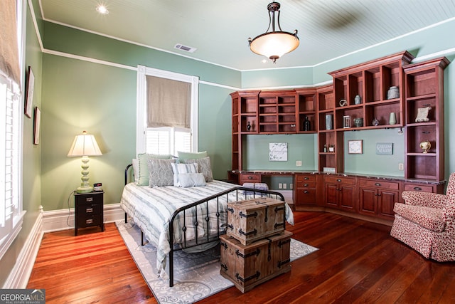 bedroom featuring dark hardwood / wood-style flooring, built in desk, and ornamental molding