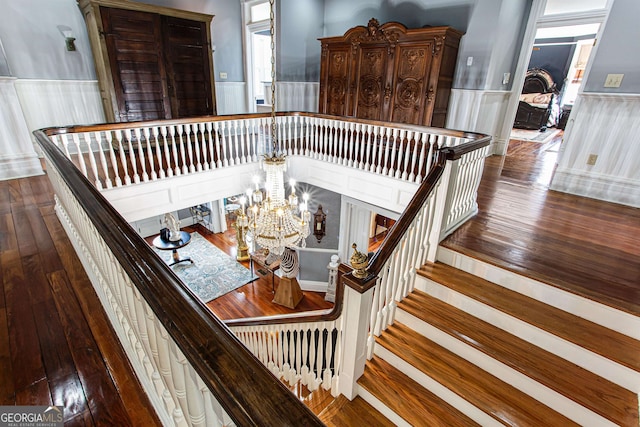 staircase with a notable chandelier and dark wood-type flooring