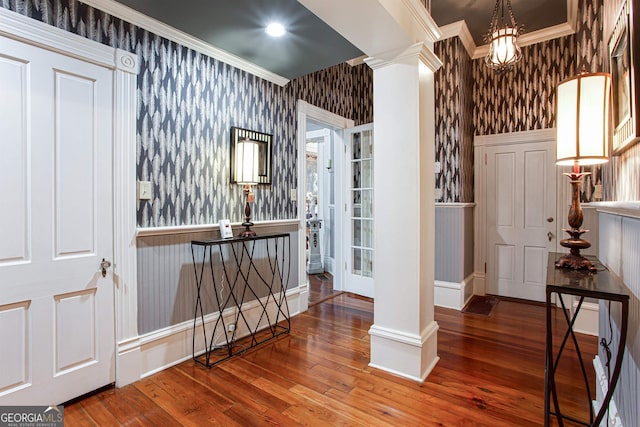 interior space featuring dark hardwood / wood-style flooring, crown molding, and decorative columns