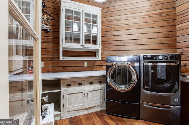 laundry area with washer and dryer, wood walls, and wood-type flooring