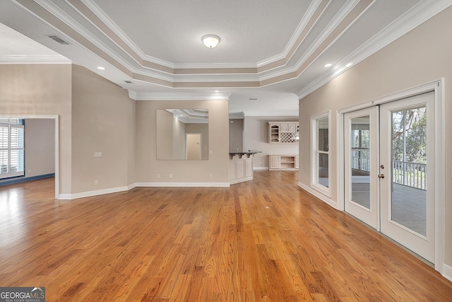 unfurnished living room with french doors, crown molding, light hardwood / wood-style flooring, and a raised ceiling