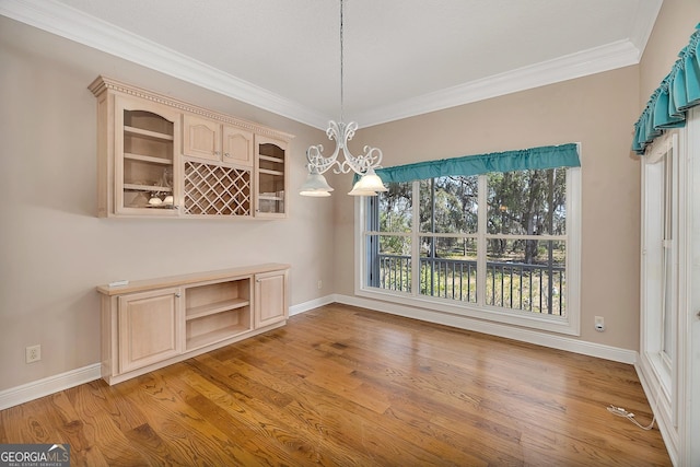 unfurnished dining area with ornamental molding, light hardwood / wood-style floors, and a notable chandelier