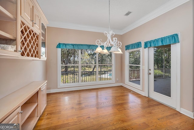 unfurnished dining area featuring an inviting chandelier, plenty of natural light, and light wood-type flooring