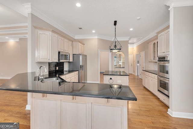 kitchen featuring sink, cream cabinetry, ornamental molding, appliances with stainless steel finishes, and light hardwood / wood-style floors