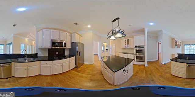 kitchen featuring decorative light fixtures, stainless steel appliances, light wood-type flooring, backsplash, and sink