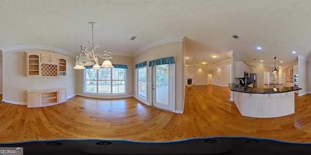 interior space featuring an inviting chandelier, hanging light fixtures, sink, white cabinetry, and light hardwood / wood-style flooring