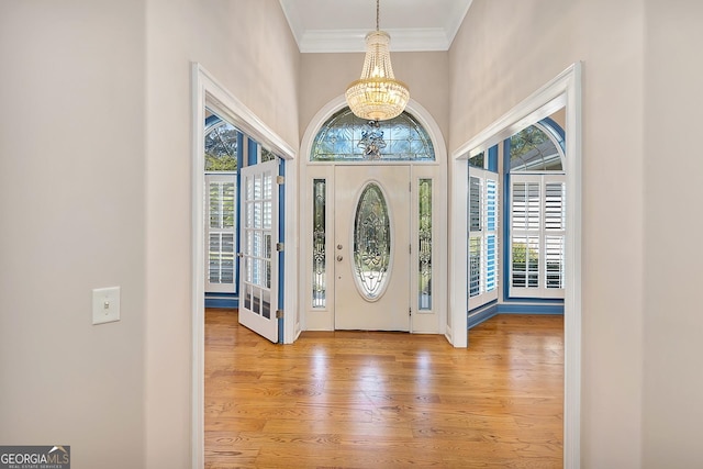 entrance foyer with ornamental molding, a chandelier, and light wood-type flooring