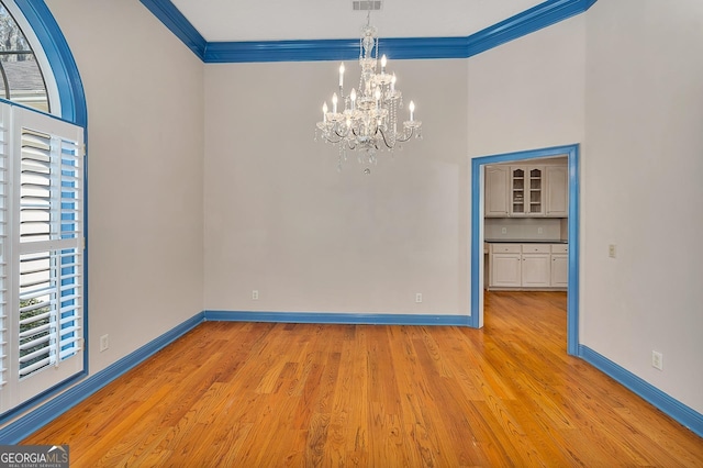 unfurnished room with a chandelier, crown molding, and light hardwood / wood-style flooring