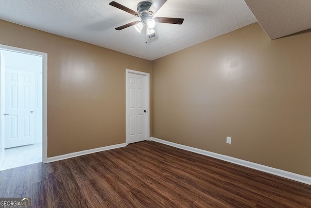 empty room with ceiling fan, a textured ceiling, and dark wood-type flooring