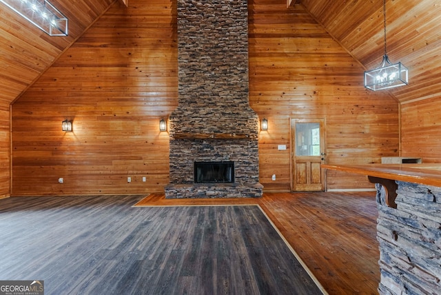 unfurnished living room with dark hardwood / wood-style floors, wooden walls, a chandelier, wooden ceiling, and a fireplace