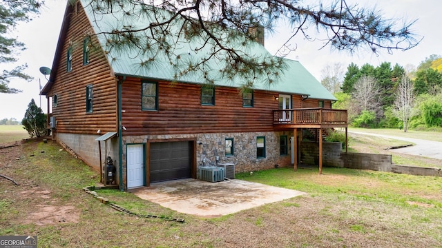 rear view of property with a yard, central AC, and a garage