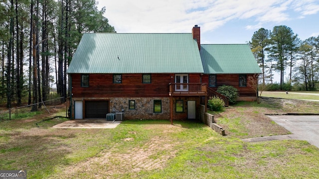 rear view of house with central AC unit, a lawn, a deck, and a garage