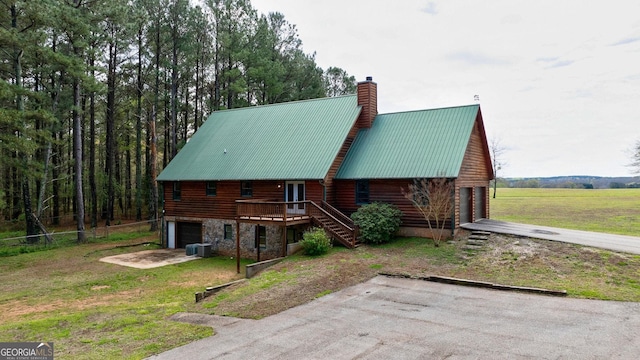 log home with a wooden deck, central AC unit, a front yard, and a garage