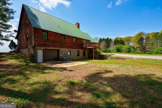 rear view of house featuring a lawn, a garage, and central AC unit