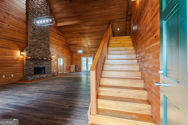 stairway featuring wood ceiling, wood walls, dark wood-type flooring, and a fireplace