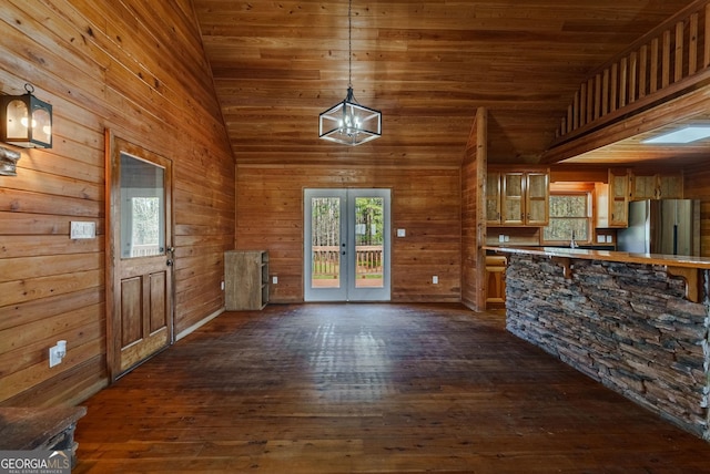 kitchen with stainless steel fridge, high vaulted ceiling, decorative light fixtures, and dark hardwood / wood-style floors