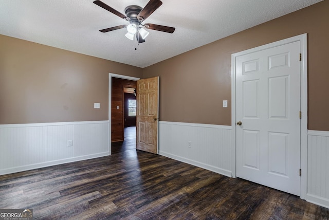 unfurnished room featuring a textured ceiling, ceiling fan, and dark hardwood / wood-style floors