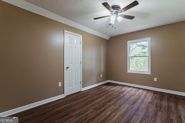 empty room with ceiling fan, dark wood-type flooring, and a textured ceiling