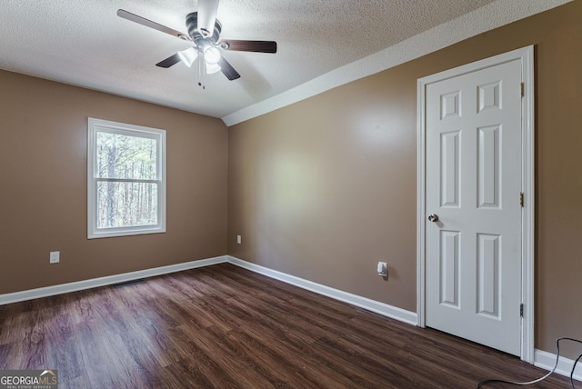 empty room with ceiling fan, a textured ceiling, and dark wood-type flooring