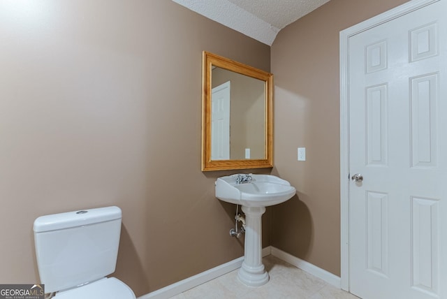 bathroom featuring tile floors, toilet, and a textured ceiling