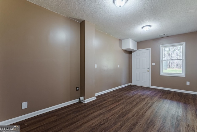 empty room with dark wood-type flooring and a textured ceiling